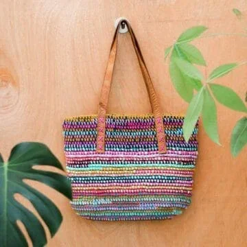 A zero waste crochet scrap yarn bag make with upcycled clothing and repurposed leather handles.