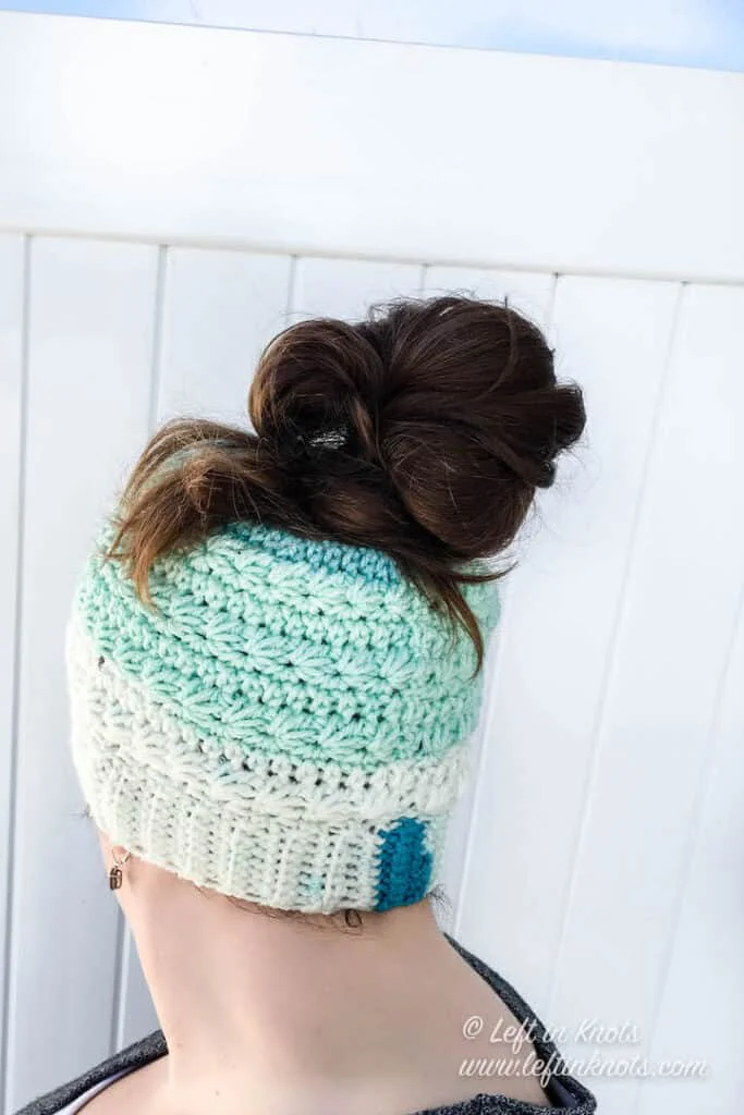A crochet messy bun beanie made with the star stitch