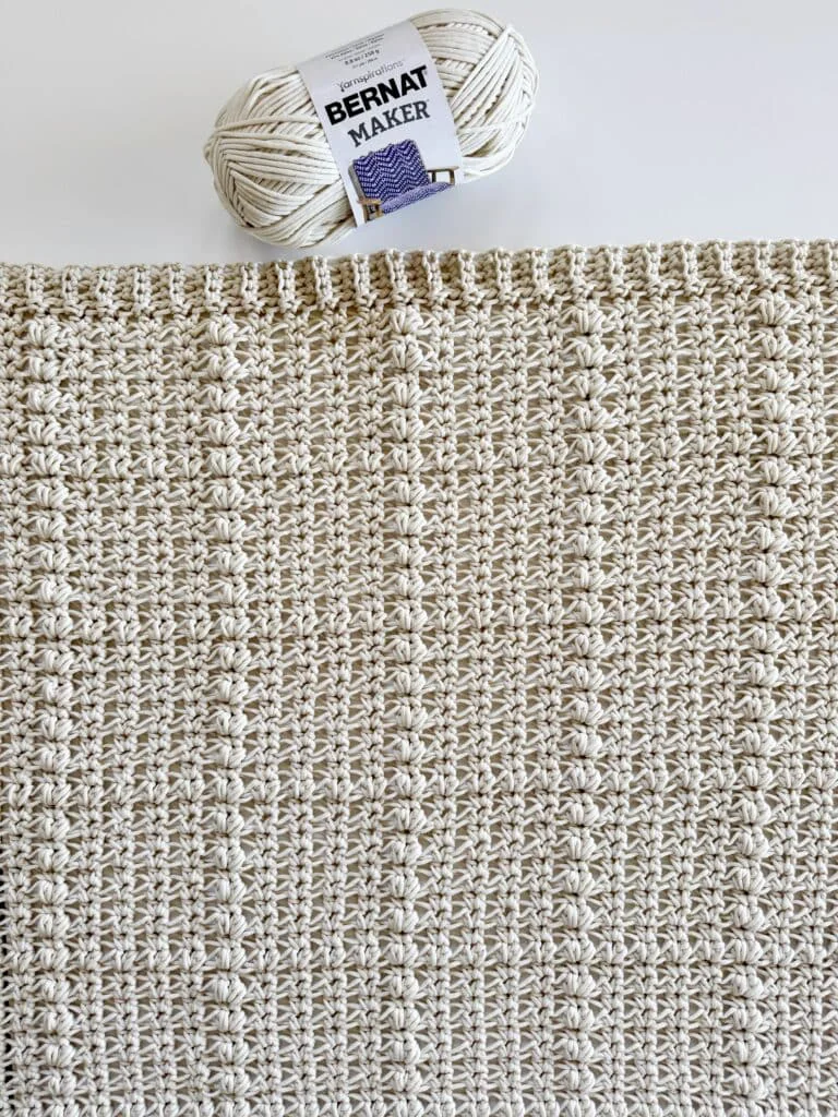 flat lay of crochet blanket with skein of yarn