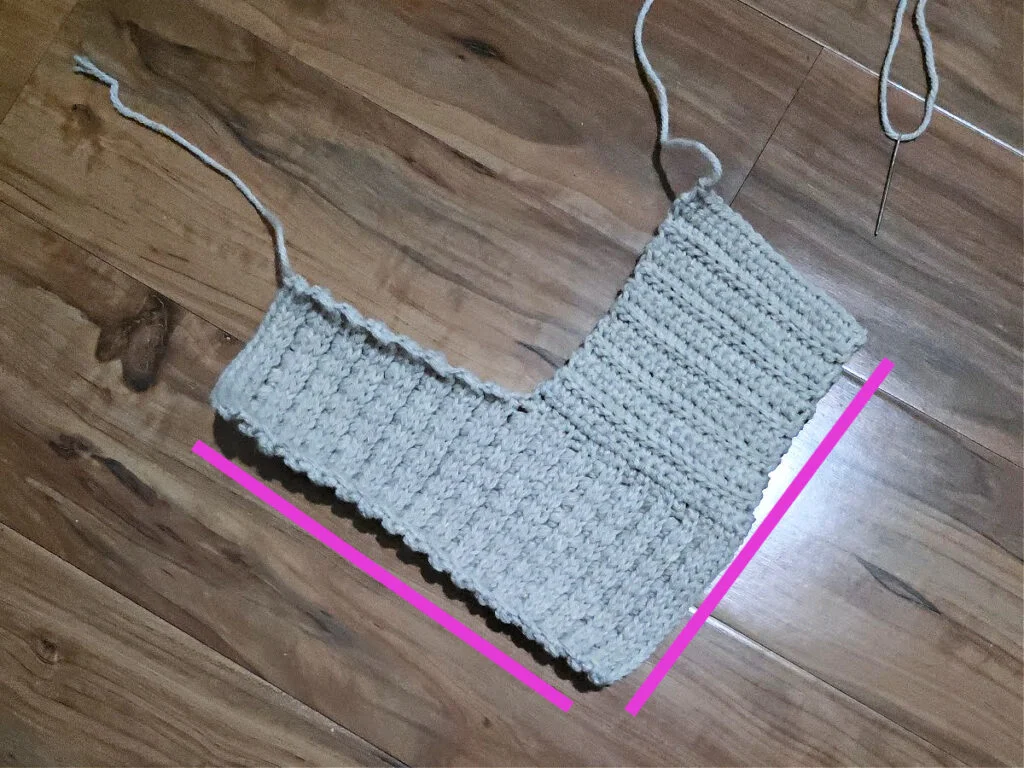 An L-shaped grey crochet strip against a wooden floor.