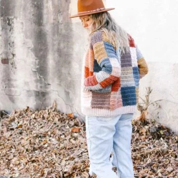 Patchwork crochet cardigan modeled by a woman outdoors.