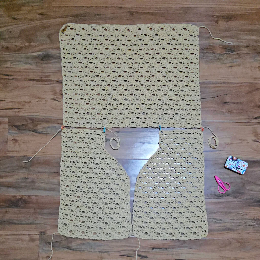 A beige colored cropped crochet cardigan in progress.