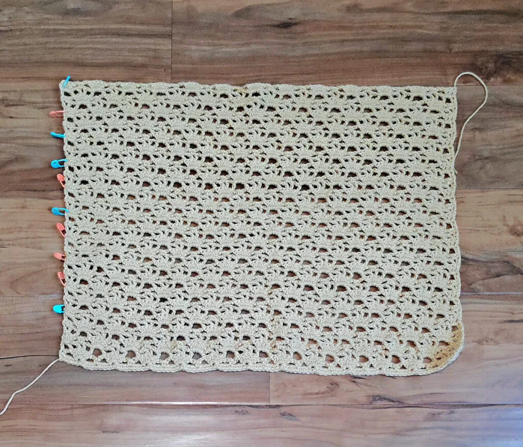 A beige colored cropped crochet cardigan in progress.