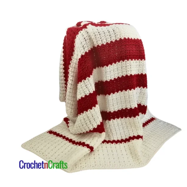 Crochet striped blanket draped over a stool.
