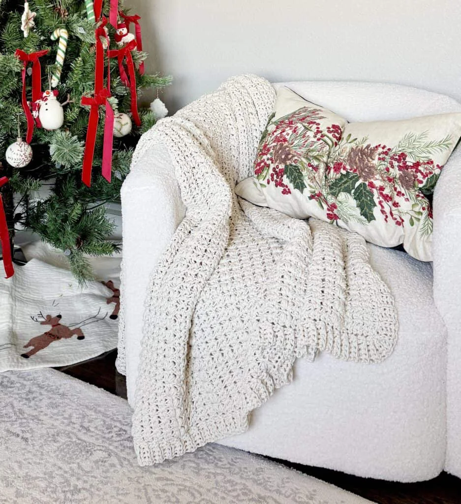 cream crochet blanket draped over white chair with tree