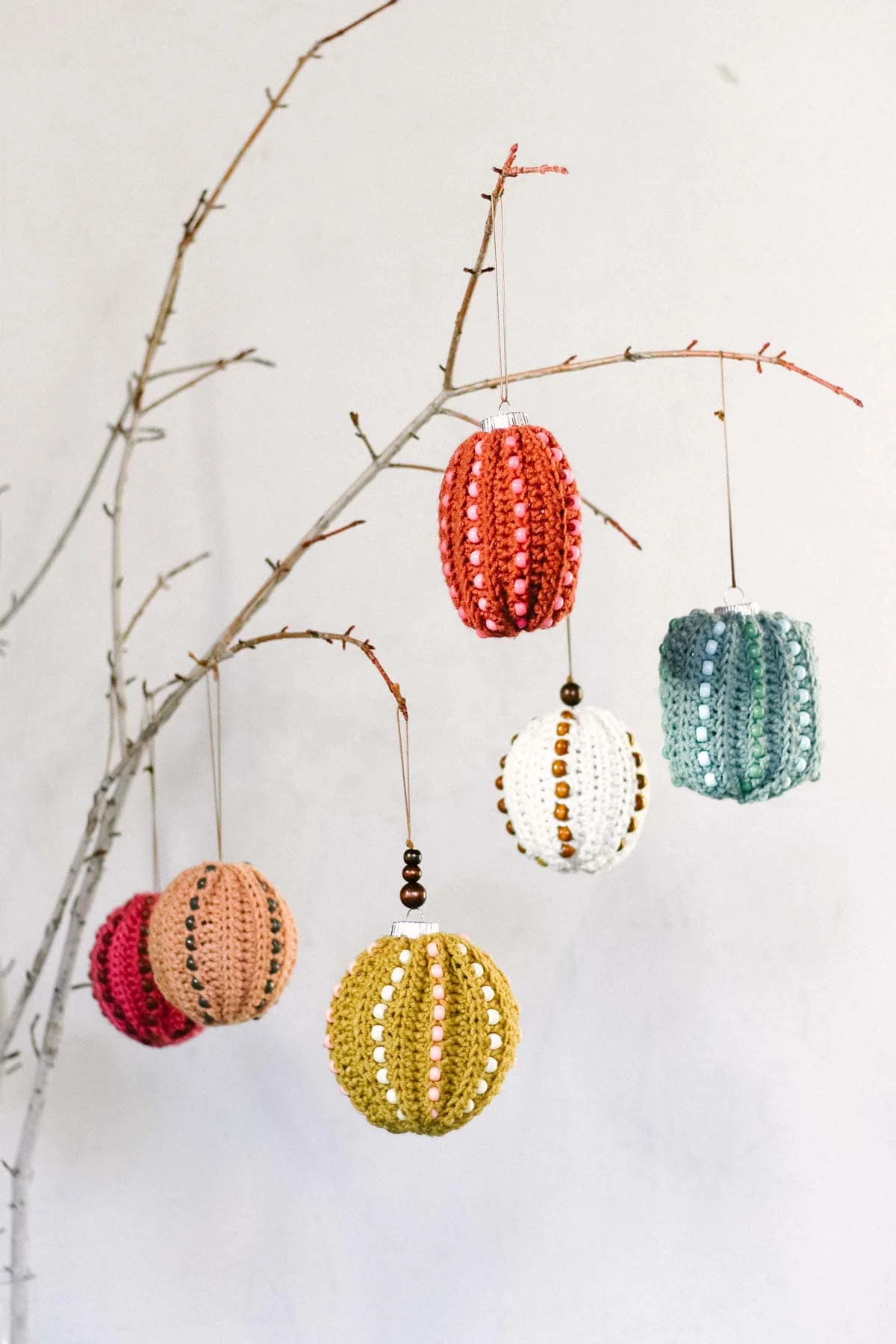 Six crochet Christmas ornaments in different colors hung on a tree.