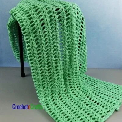 Lacy Double V-Stitch Crochet Lapghan Draped Over a Stool