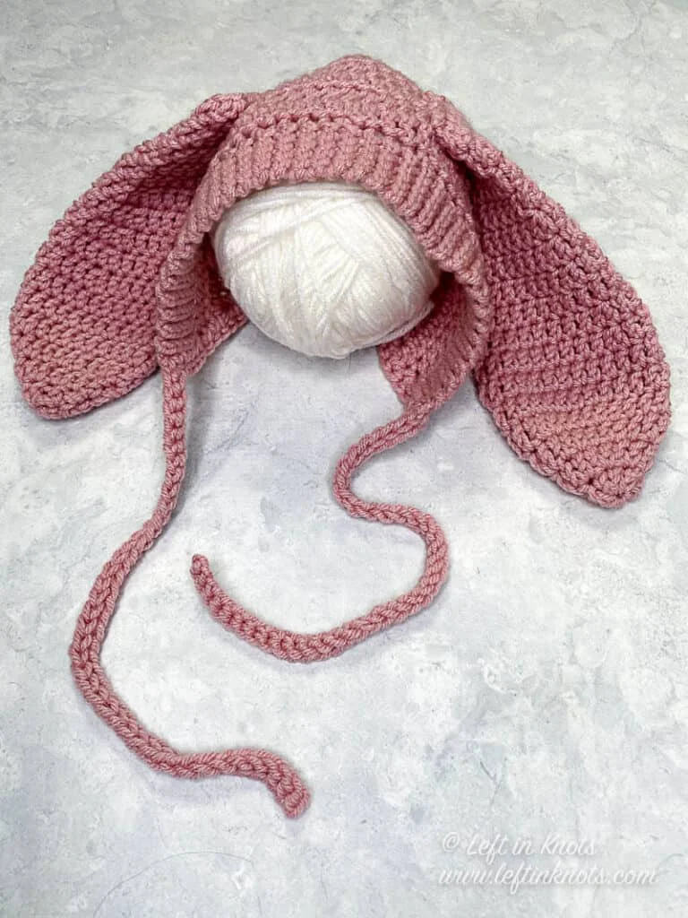 a pink bunny bonnet crocheted in a newborn size